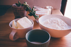 Raw ingredients of flour and dairy places in a bowl and cup.